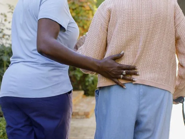 Companion caregiver supporting elderly client on a walk